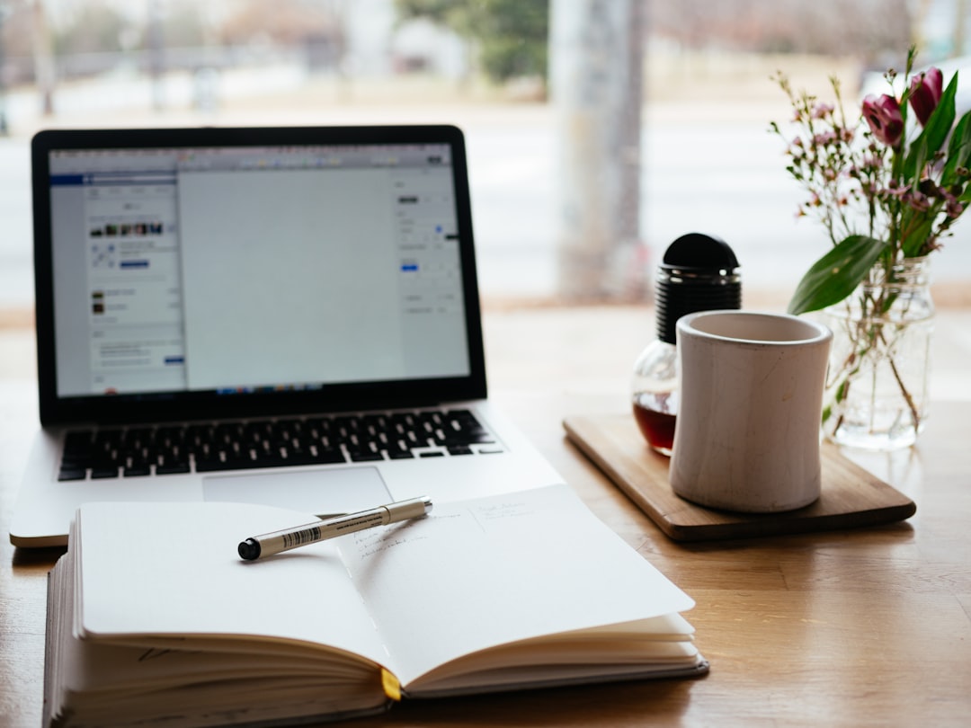 A laptop and an open notebook on a desk, mid-draft