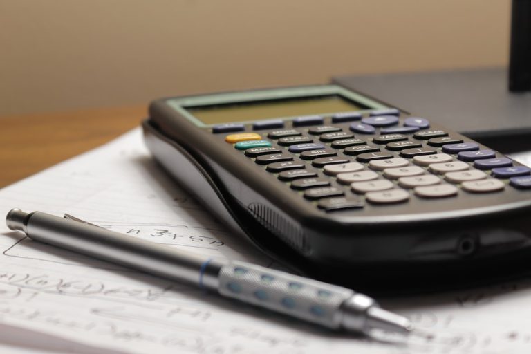 A calculator and pen on a printed invoice